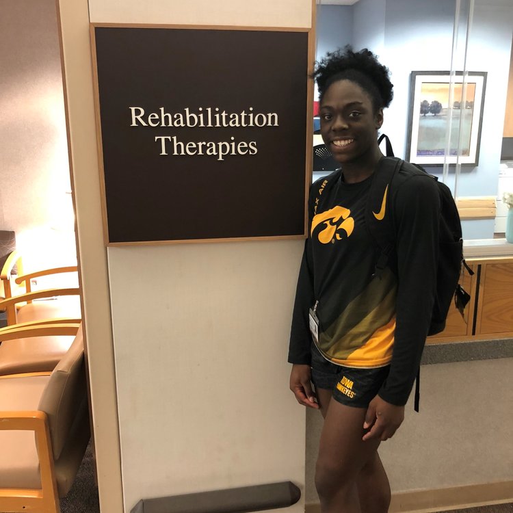 Student athlete standing next to a sign for Rehabilitation Therapy