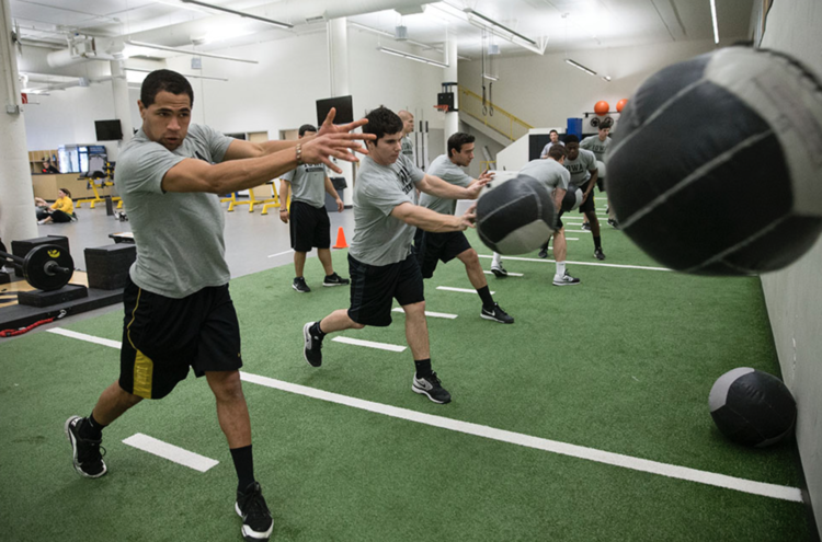 student-athletes throwing medicine balls at a wall